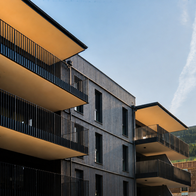 Modernes Wohngebäude mit übereinander gestapelten Balkonen und blauem Himmel