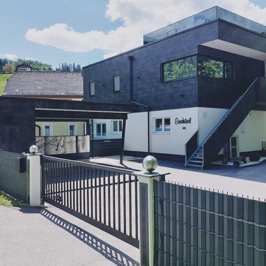 Modernes zweistöckiges Gebäude mit schwarzer Fassade und Toreingang