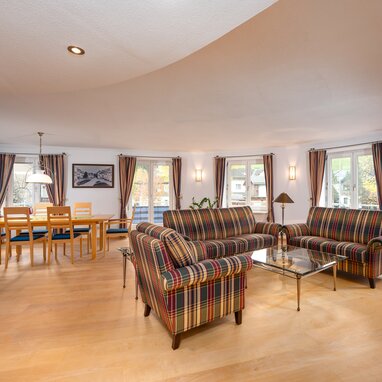 Großzügiges Wohn- und Esszimmer mit karierten Sofas und Holzmöbeln