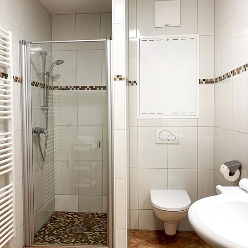 Helles Badezimmer mit Glasdusche, Toilette und Waschbecken