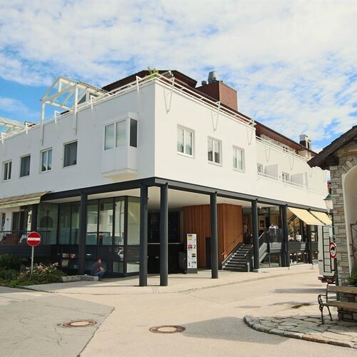 Moderner weißer Gebäudekomplex mit Glasfronten und kleinem Steinschrein in der Nähe