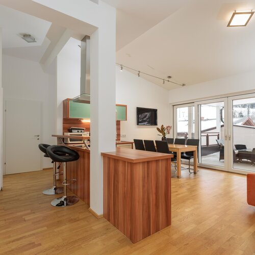 Offener Wohnbereich mit Kücheninsel, Esstisch und Balkonzugang