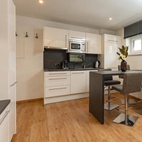 Moderne weiße Küche mit Insel und Essecke