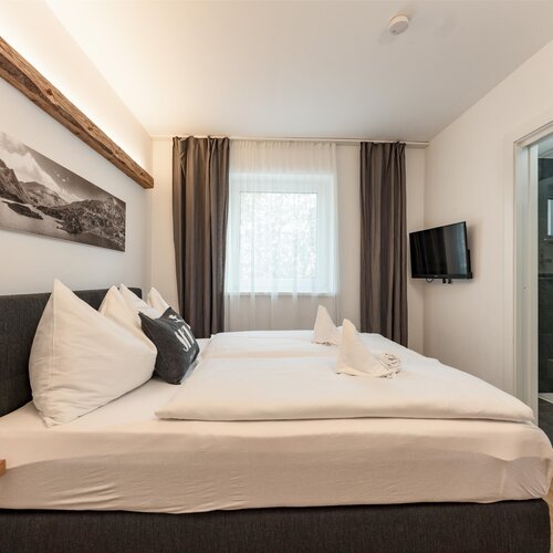 Modernes Hotelzimmer mit großem Bett und eigenem Bad