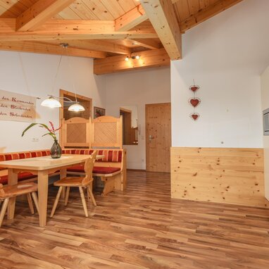 Holzbasierter Essbereich mit roter Polsterbank und Stühlen