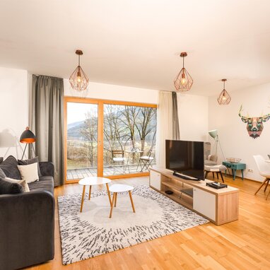 Modernes Wohnzimmer mit grauer Couch, Glastüren und geometrischer Wandkunst