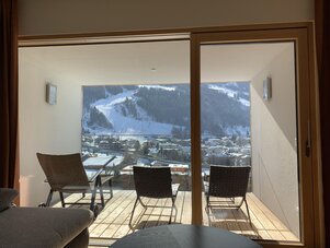 Balkon mit Korbsesseln und Blick auf verschneites Bergdorf