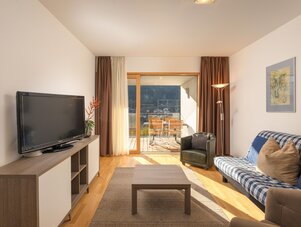 Modernes Wohnzimmer mit Flachbildfernseher, Sofa und Balkon