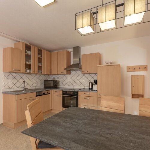 Heller Küchenbereich mit Holzmöbeln, Tisch und Geräten