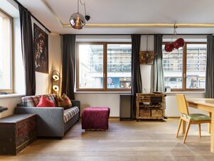 Gemütliches Wohnzimmer mit grauem Sofa und karierten Kissen.