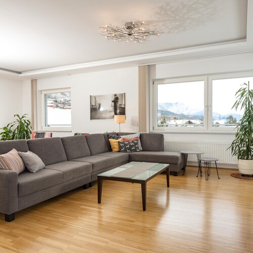 Helles modernes Wohnzimmer mit grauer Eckcouch und Bergblick