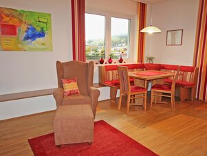 Wohnzimmer mit rotem Akzent-Essbereich und Sessel