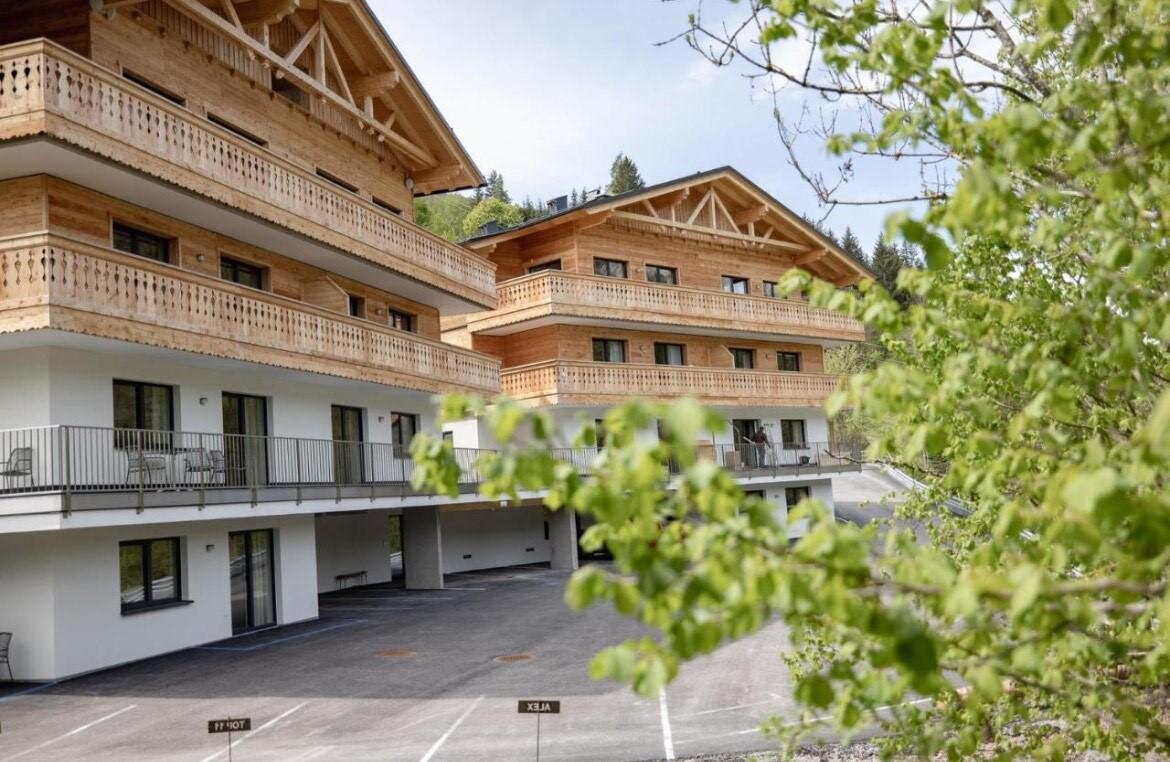 Chaletartiges Holzwohngebäude mit mehreren Balkonen im Bild