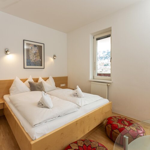 Großes Doppelbett mit weißer Bettwäsche in hellem Zimmer mit Fenster