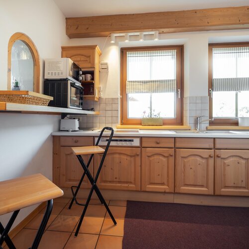 Gemütliche rustikale Küche mit Holzkabinett und zwei Fenstern | © TIEBER