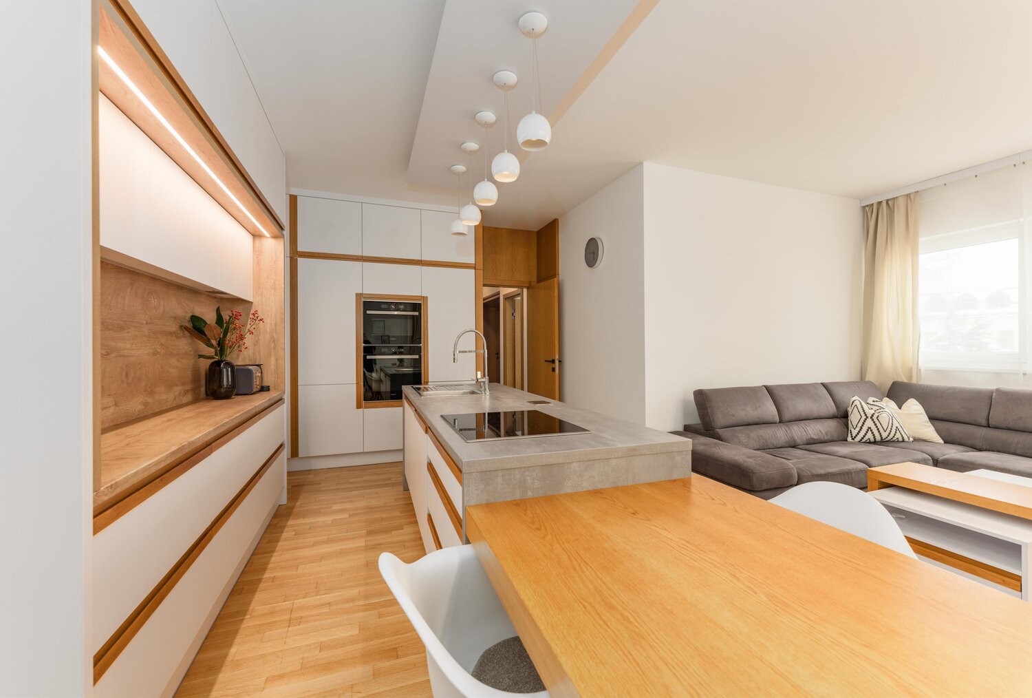 Moderne Küche mit Insel, Pendelleuchten und Wohnzimmer