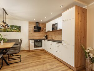 Offener Küchenbereich mit weißen Schränken, Holzakzenten und Essbereich