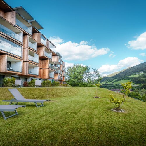Modern wooden apartment building with balconies on grassy hillside