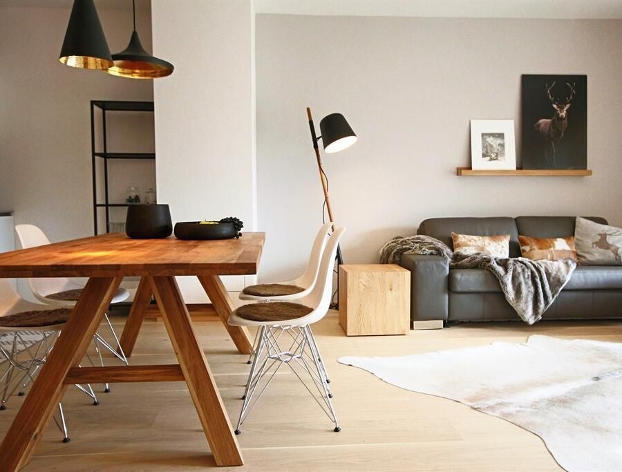 Bright open-plan living and dining area with wooden table and sofa