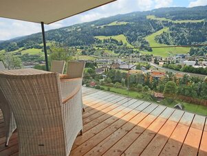 Balkon mit Korbsesseln und Blick auf Dorf und Hügel
