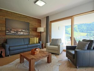 Gemütliches Wohnzimmer mit Holzwand, Sofa und großen Fenstern