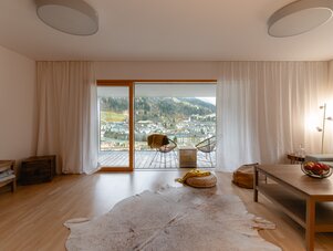 Living room with sliding glass doors to balcony overlooking town and hills