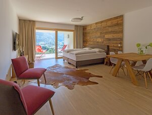 Bright hotel room with balcony, bed, and seating