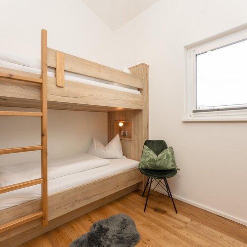 Hölzerne Etagenbetten mit Leiter in hellem Schlafzimmer