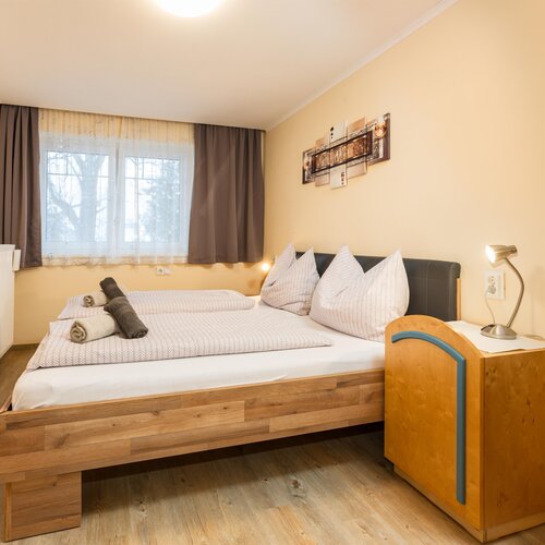 Gemütliches Hotelzimmer mit Doppelbett, Kissen und Nachttischlampe.