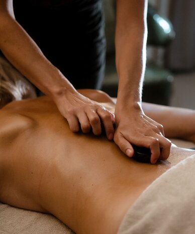 Therapist performing hot stone massage on back