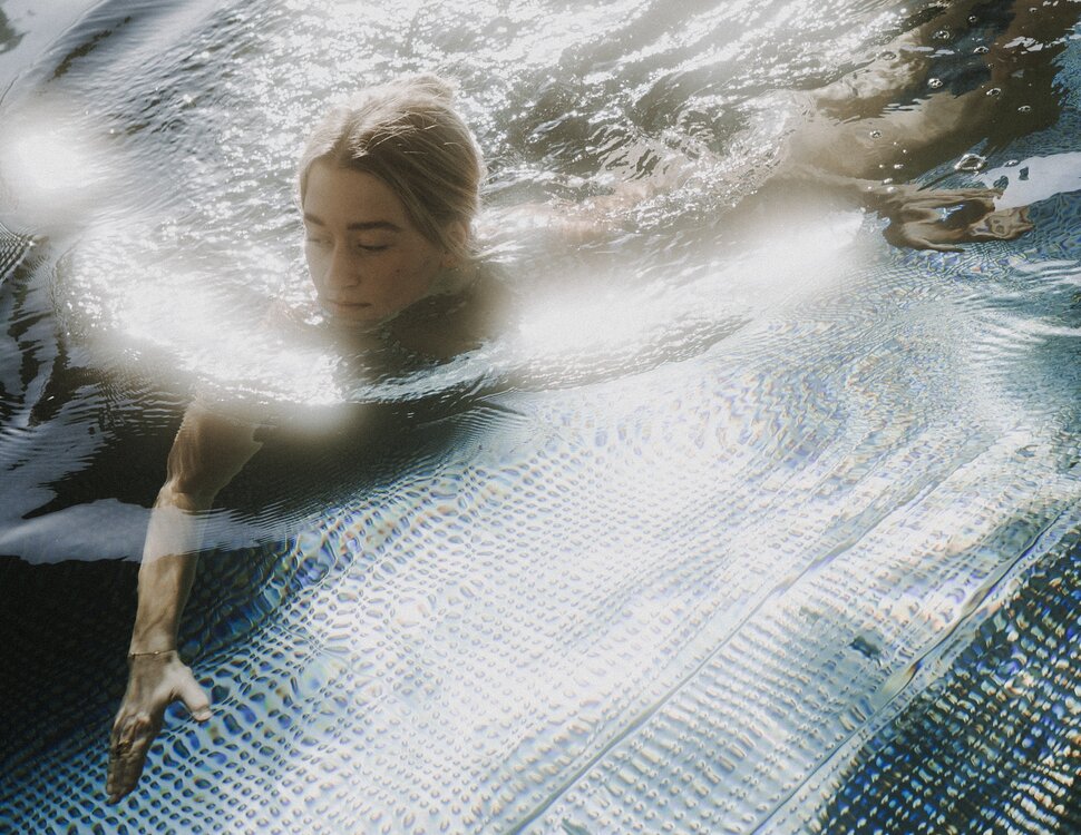 Person swimming underwater near pool edge with metal grid bottom