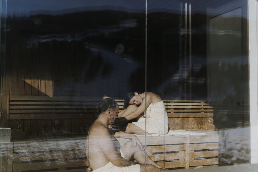 Two people in a wooden sauna, sitting on benches