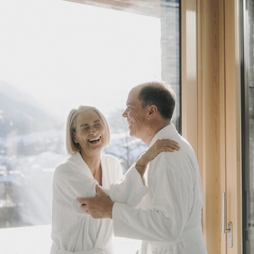 Elderly couple smiling in white bathrobes indoors