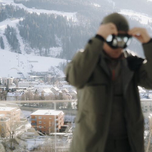 Person adjusts ski goggles in front of snowy mountain town